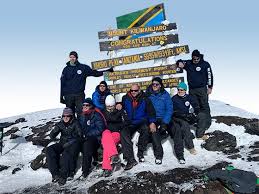 Group budget climbers celebrating at Uhuru Peak summit on Mount Kilimanjaro